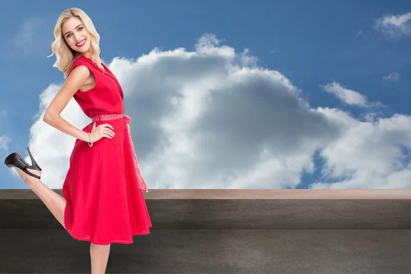 Composite image of smiling blonde standing hands on hips — Stock Photo, Image