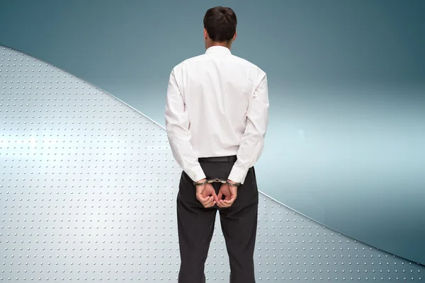 Composite image of rear view of young businessman wearing handcuffs — Stock Photo, Image