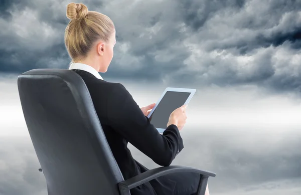 Composite image of businesswoman sitting on swivel chair with tablet — Stock Photo, Image