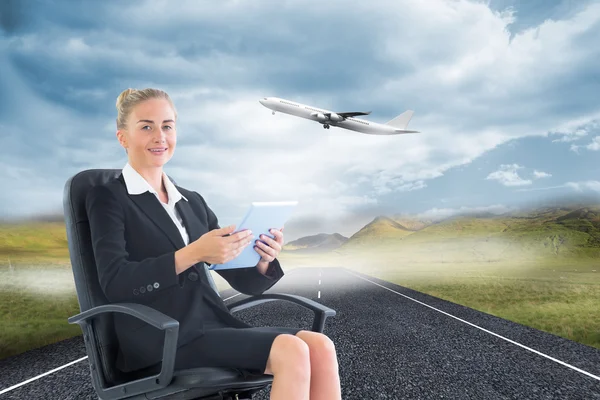 Composite image of businesswoman sitting on swivel chair with tablet — Stock Photo, Image