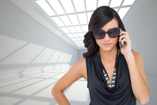 Composite image of serious elegant brunette wearing sunglasses — Stock Photo, Image