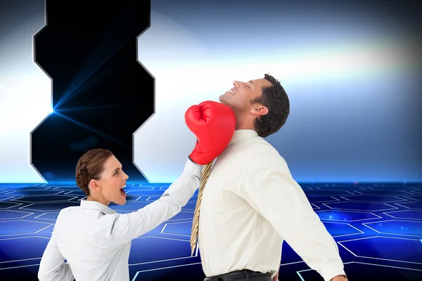 Businesswoman hitting a businessman with boxing gloves — Stock Photo, Image