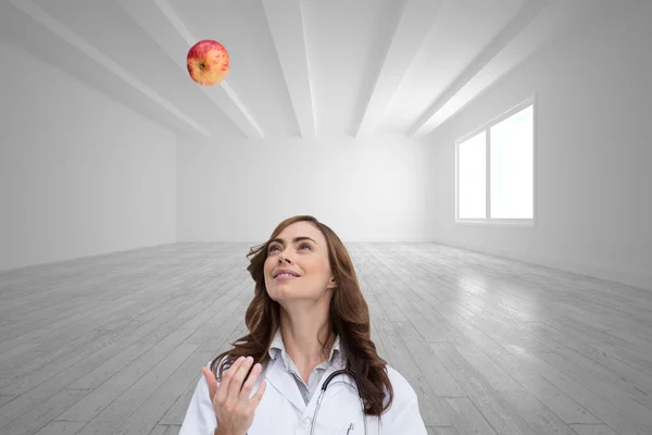 Imagem composta de médico feliz jogando maçã — Fotografia de Stock