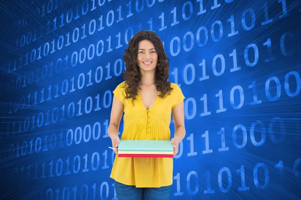 Composite image of smiling curly haired brunette holding notebooks — Stock Photo, Image