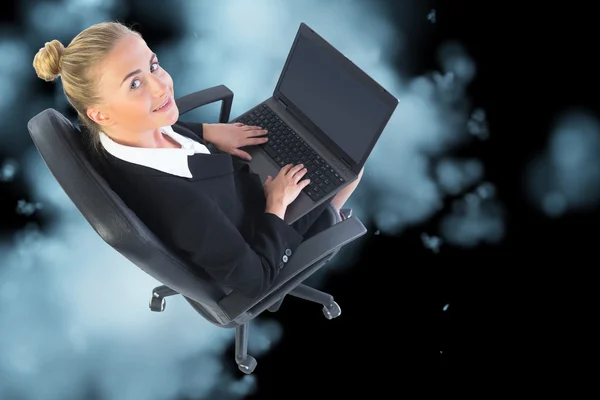 Blonde businesswoman sitting on swivel chair with laptop — Stock Photo, Image