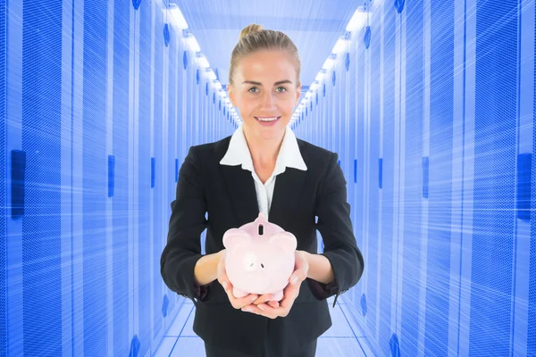 Composite image of businesswoman holding pink piggy bank — Stock Photo, Image