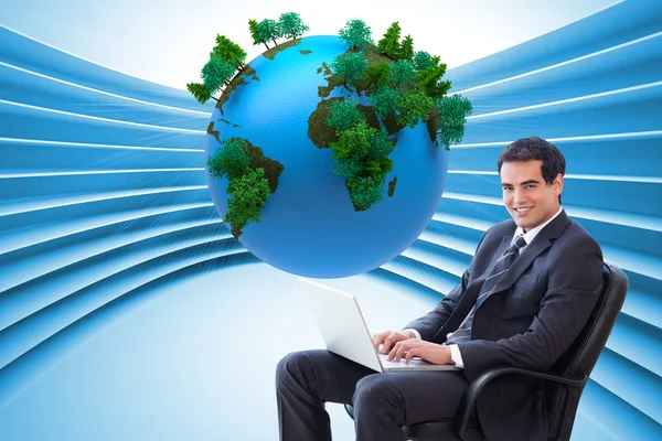 Young businessman sitting on an armchair working with a laptop — Stock Photo, Image