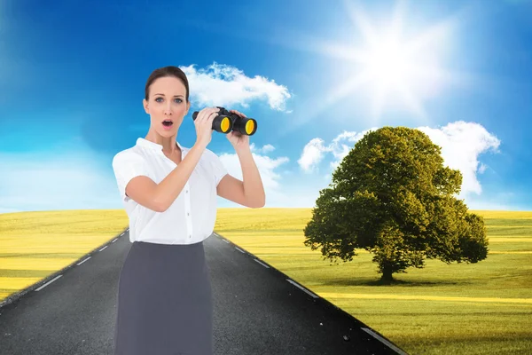 Astonished elegant businesswoman holding binoculars — Stock Photo, Image