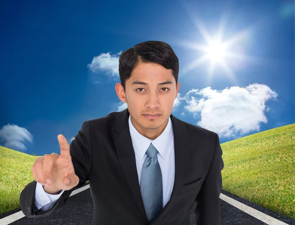 Composite image of serious asian businessman pointing — Stock Photo, Image