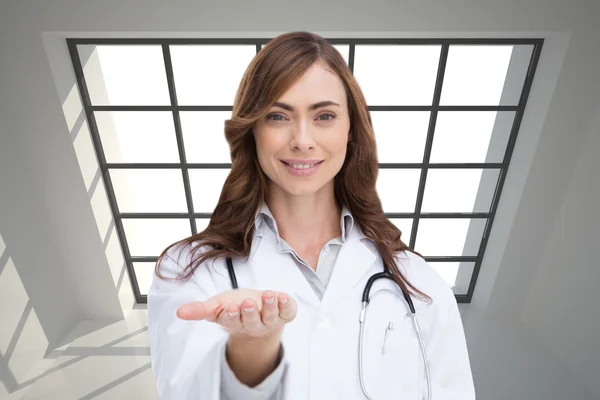 Composite image of smiling doctor presenting her hand — Stock Photo, Image