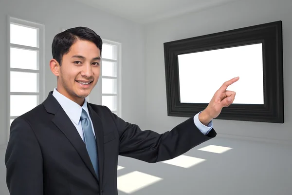 Obraz kompozytowy uśmiechający się azjatycki biznesmen, wskazując — Zdjęcie stockowe