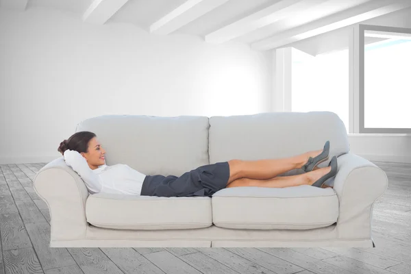 Улыбающаяся деловая женщина, лежащая на диване — стоковое фото