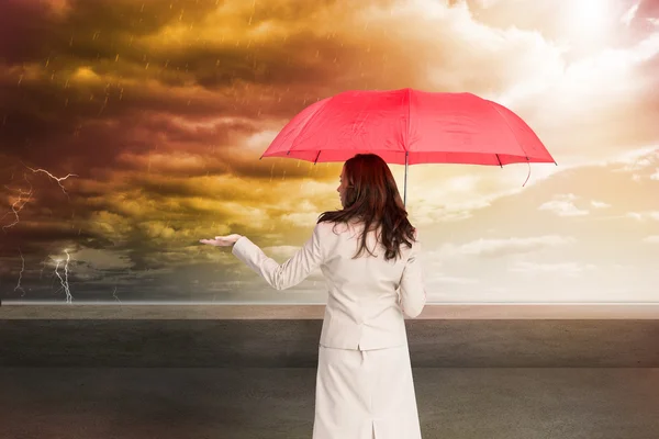 Composite image of businesswoman holding umbrella — Stock Photo, Image