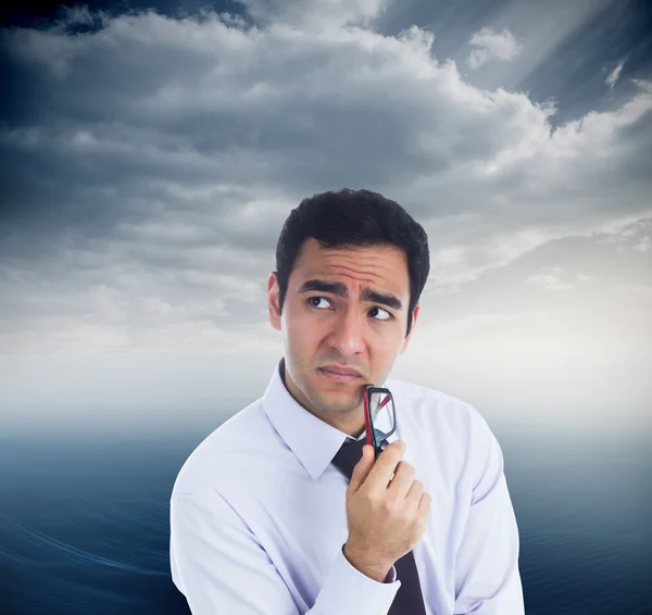 Composite image of thinking businessman holding glasses — Stock Photo, Image