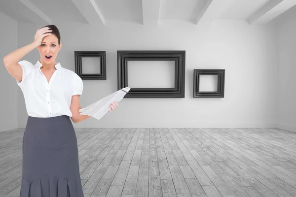 Composite image of shocked classy businesswoman holding newspaper — Stock Photo, Image