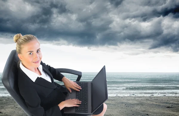 Composite image of businesswoman sitting on swivel chair with laptop — Stock Photo, Image