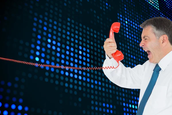 Businessman screaming directly into the red telephone handset — Stock Photo, Image