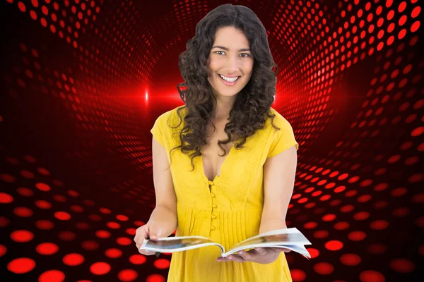 Cheerful curly haired brunette reading magazine — Stock Photo, Image