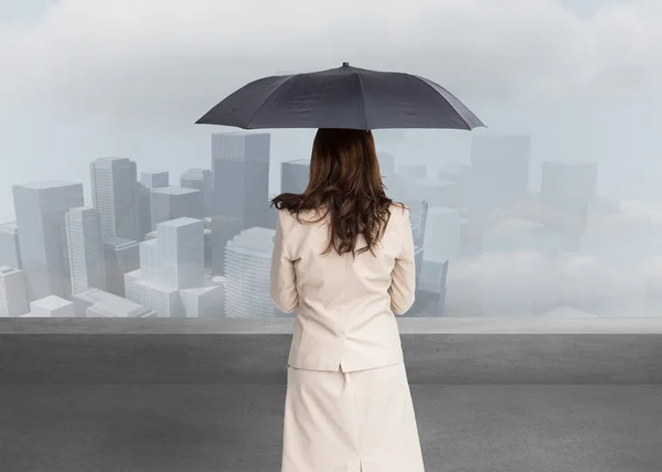 Composite image of rear view of classy businesswoman holding umbrella — Stock Photo, Image