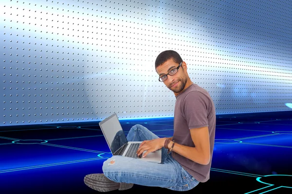 Seorang pria memakai kacamata duduk di lantai menggunakan laptop — Stok Foto