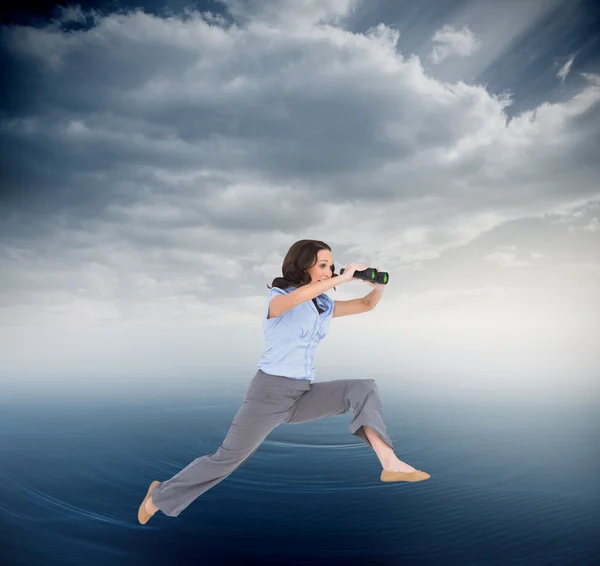 Businesswoman jumping while holding binoculars — Stock Photo, Image