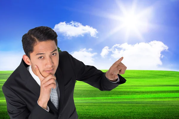 Composite image of thoughtful asian businessman pointing — Stock Photo, Image