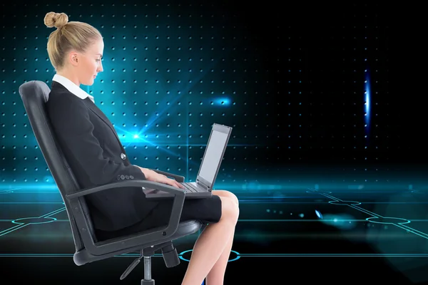 Dizüstü bilgisayar ile döner sandalye üzerinde oturan sarışın iş kadını — Stok fotoğraf