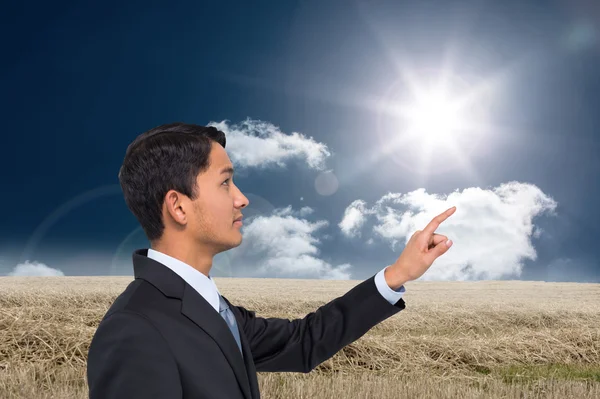 Composite image of serious asian businessman pointing — Stock Photo, Image