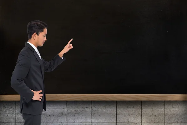 Composite image of unsmiling asian businessman pointing — Stock Photo, Image