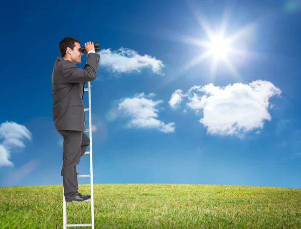 Businessman standing on ladder holding binoculars — Stock Photo, Image