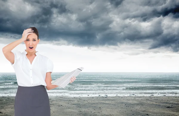 Samengestelde afbeelding van geschokt stijlvolle zakenvrouw bedrijf newspape — Stockfoto