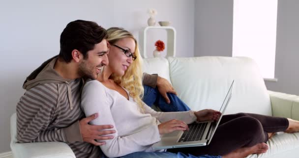 Paret sitter i soffan med den bärbara datorn — Stockvideo