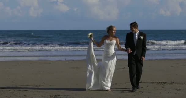 Pareja de recién casados caminando por la playa — Stockvideo