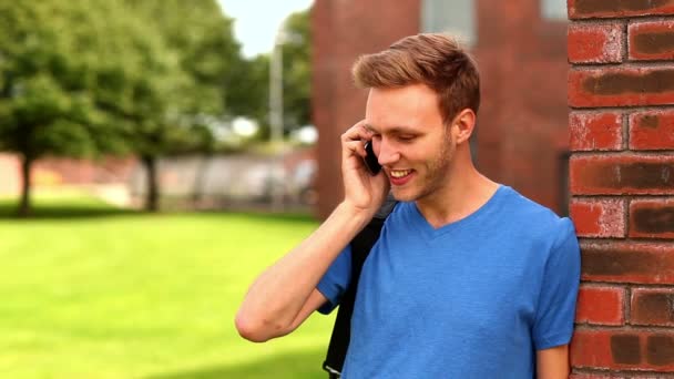 Щасливий студент розмовляє по телефону зовні — стокове відео