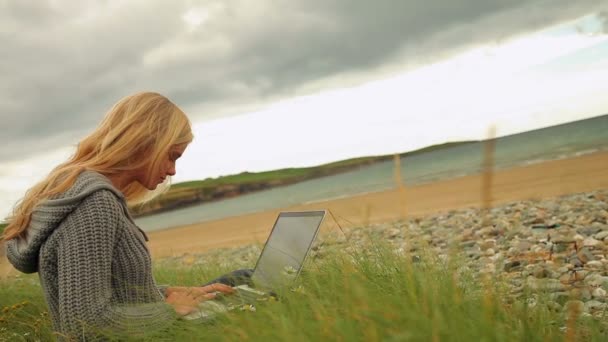 Blondynka za pomocą laptopa przy plaży — Wideo stockowe