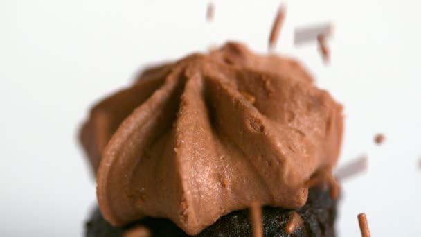 Chocolate sprinkles falling onto chocolate cupcake — Stock Video