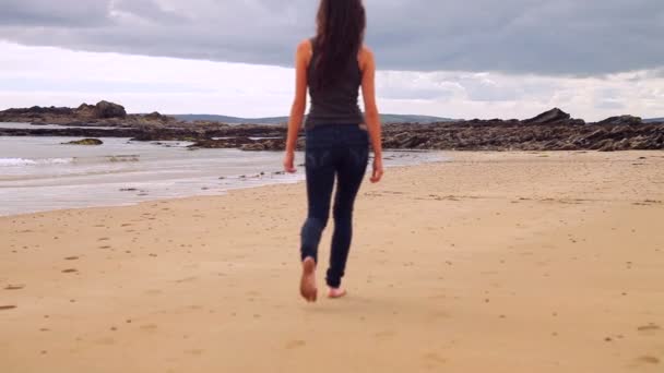 Morena andando ao longo da água pela praia — Vídeo de Stock