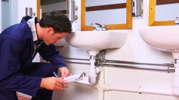 Handsome plumber looking at sink holding clipboard — Stock Video