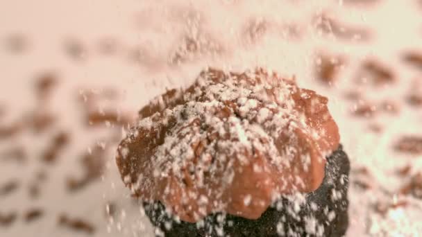Просеивание сахара на шоколадных глазированных кексах — стоковое видео