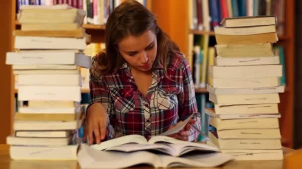 Figyelmes hallgató tanul a könyvek körül könyvtár — Stock videók