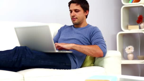 Hombre usando su cuaderno sentado en el sofá — Vídeos de Stock