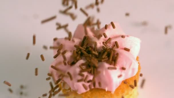 Cioccolato spruzza cadere su rosa glassato cupcake — Video Stock