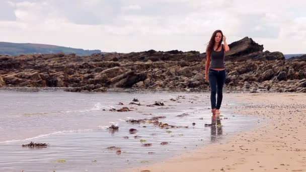 Brunette wandelen langs het water aan het strand — Stockvideo