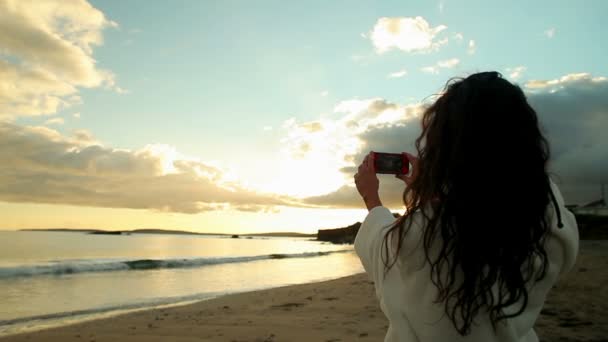 Brunette het nemen van een foto van de zonsondergang op haar smartphone — Stockvideo