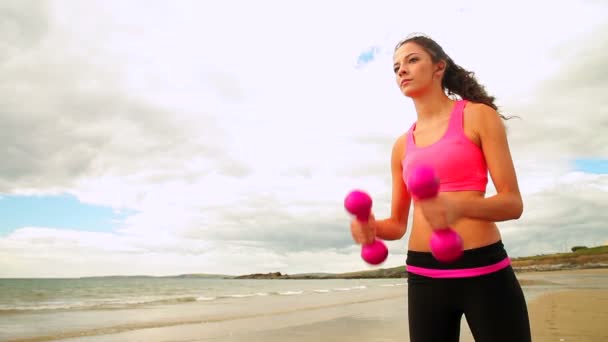 Linda morena levantando halteres na praia — Vídeo de Stock