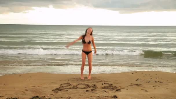 Gorgeous brunette dancing around with 2013 written in the sand — Stock Video