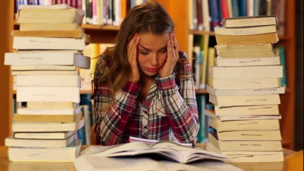 Hallgató tanul, és jegyzeteket a könyvtárban könyvek körül — Stock videók
