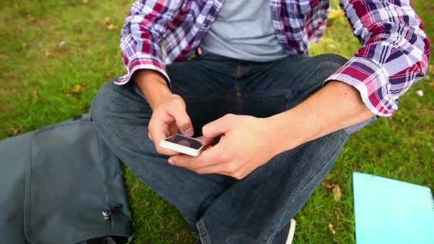 Étudiant assis sur l'herbe textos au téléphone — Video