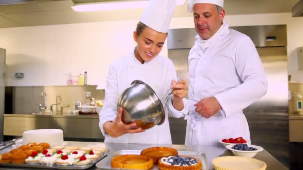 Capo chef guardando il suo studente versare crema in caso di pasticceria — Video Stock