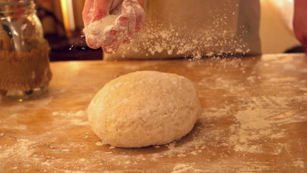 Female hand sprinkling flour on ball of dough on a floury surface — Stock Video